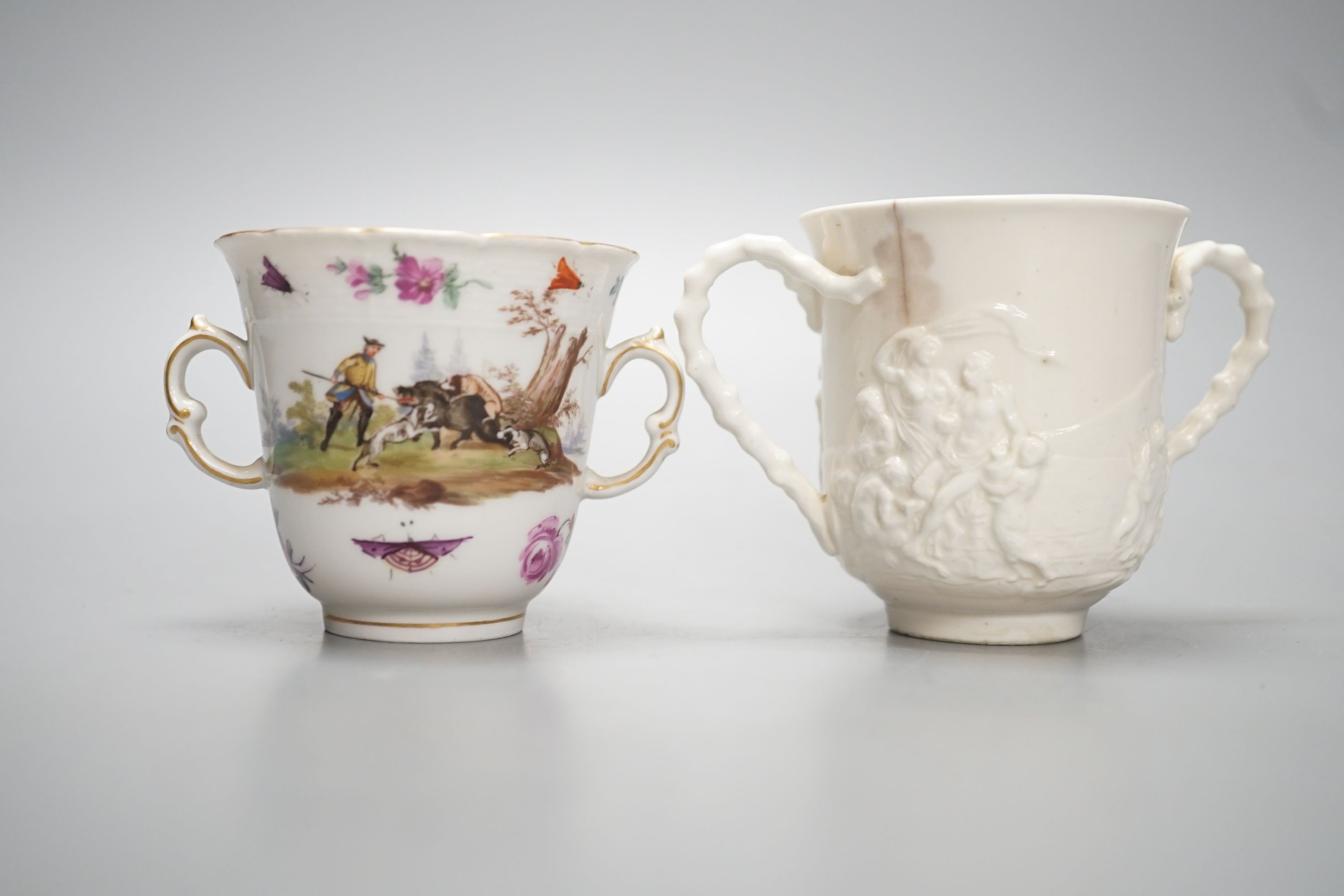 A late 18th / early 19th century Berlin two handled chocolate cup, 7cm high, painted with hunting scenes and an 18th century Doccia two handled chocolate cup moulded in Istoriato style.